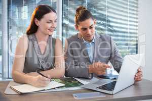 Business executives discussing over laptop at desk