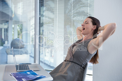 Tired female executive relaxing at table