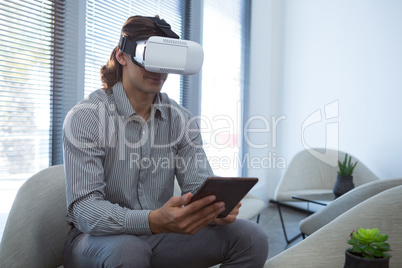 Male executive using digital tablet and virtual reality headset