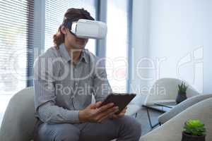 Male executive using digital tablet and virtual reality headset