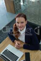 High angle view of female executive sitting with laptop at desk