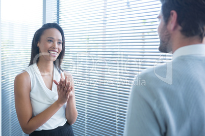 Male and female executives interacting with each other near window