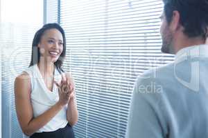 Male and female executives interacting with each other near window