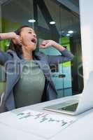 Tired businesswoman yawning at table