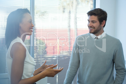 Male and female executives interacting with each other near window