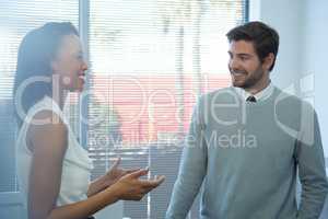 Male and female executives interacting with each other near window
