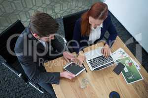 High angle view of business executives discussing over digital tablet