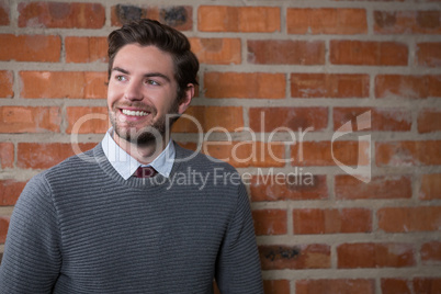 Smiling executive posing against brick wall