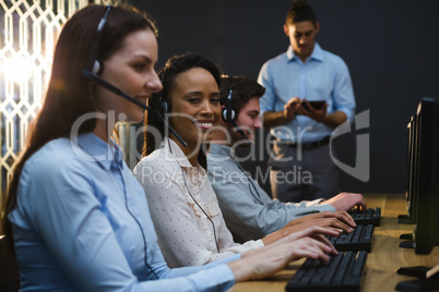 Business executives with headsets using computers at desk