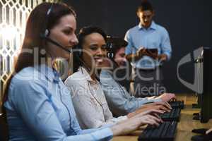 Business executives with headsets using computers at desk