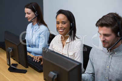 Business executives with headsets using computers at desk