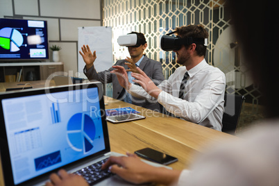 Businessmen using virtual reality headset in conference room