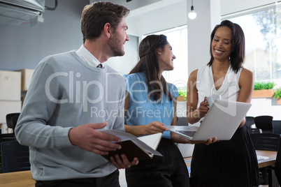 Executives smiling and discussing over laptop