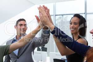 Group of executives giving high five at office