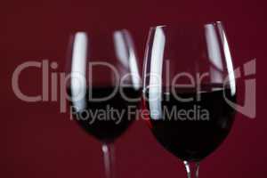Two wine glasses against red background