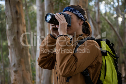 Hiker woman clicking a photo in forest