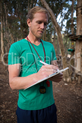 Athletic man taking notes standing in forest