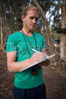 Athletic man taking notes standing in forest