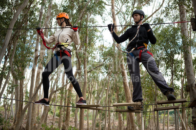 Couple holding zip line while crossing obstacle