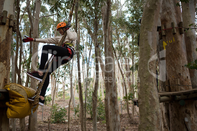 Woman wearing safety helmet swinging on rope trying to hold other rope