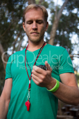 Trainer holding stop watch in his hand in the forest