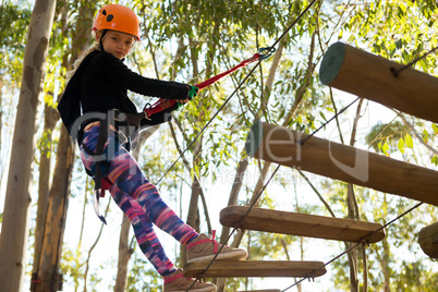 Little girl wearing helmet walking on wooden bridge