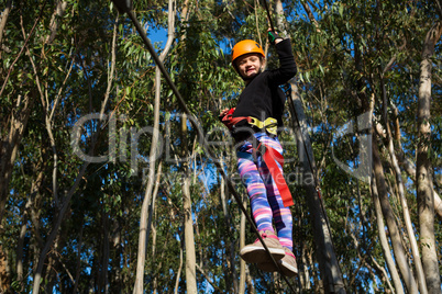 Little girl wearing helmet crossing zip line