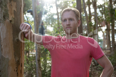 Man standing in forest taking support of tree