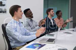 Happy executive applauding during meeting