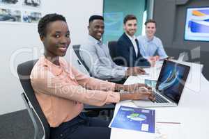 Male and female executives using laptop during meeting