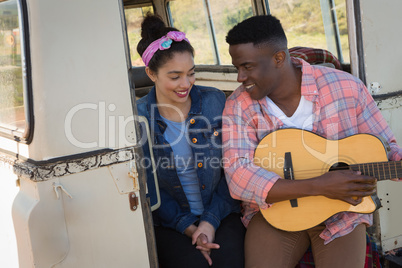 Man playing guitar for woman at countryside
