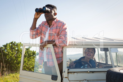 Man looking through binoculars at countryside