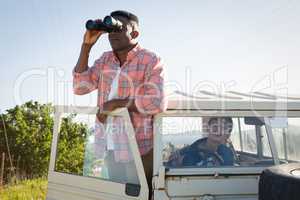 Man looking through binoculars at countryside