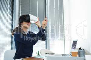 Female executive using virtual headset at desk