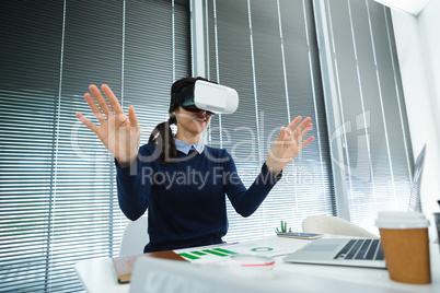 Female executive using virtual headset at desk
