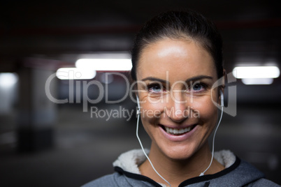 Smiling fit woman listening to music in underground parking area