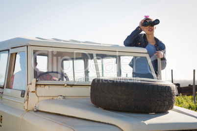 Woman looking through binoculars at countryside