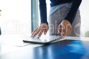 Mid section of female executive using digital tablet at desk