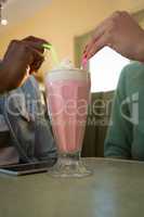Couple holding drinking straw in milkshake at restaurant