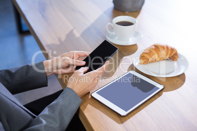 Mid section of female executive using mobile phone at desk