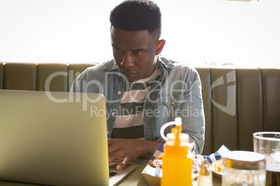 Young man sitting on couch using his laptop