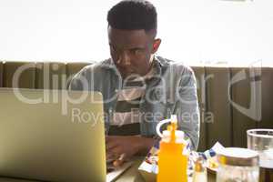 Young man sitting on couch using his laptop