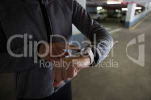 Fit woman using smartwatch in underground parking area