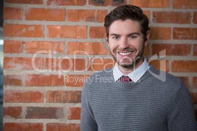 Smiling executive standing against brick wall in the office