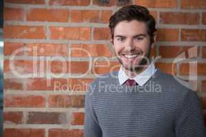 Smiling executive standing against brick wall in the office