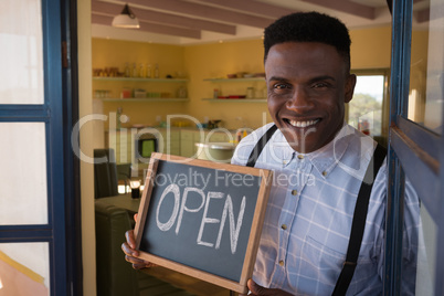 Male owner holding chalkboard with open sign