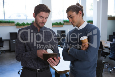 Male executives discussing over digital tablet