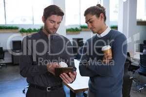 Male executives discussing over digital tablet