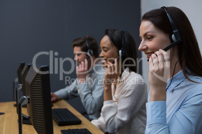 Business executives with headsets using computers at desk