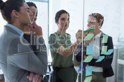 Group of executives discussing over sticky notes on the wall at office